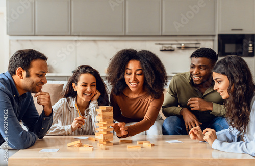 Young multiethnic friends playing board game having fun at home photo