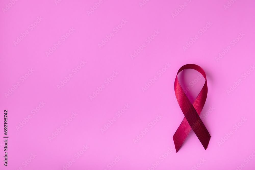 Red ribbon on a pink delicate background, top view with space for text. Campaign to help people facing cancer. Red ribbon on a pink delicate background, top view with space for text. Campaign to help people facing cancer.