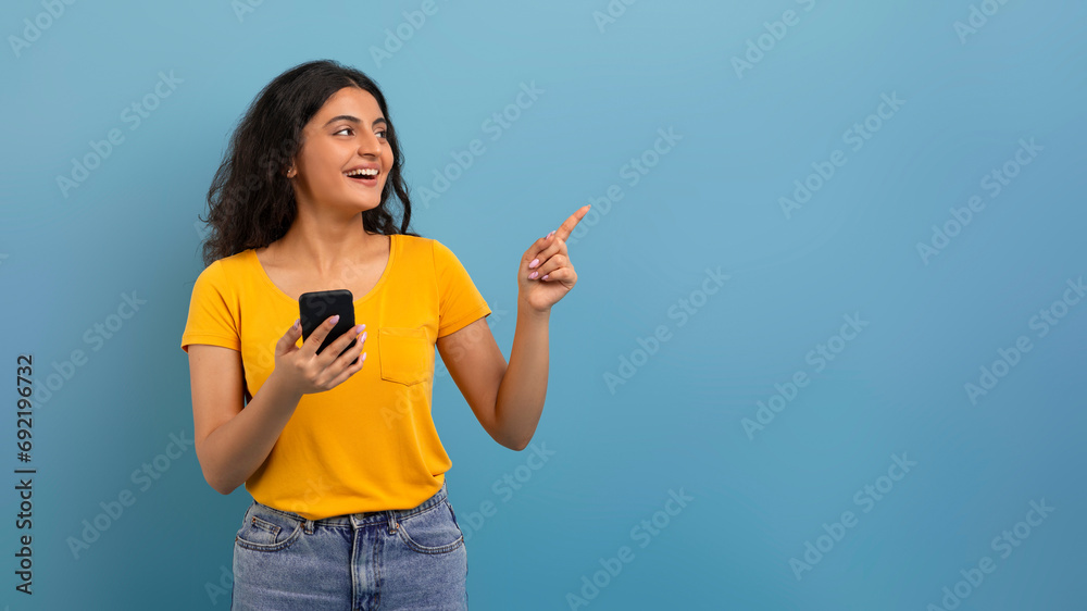 Positive young indian woman with smartphone showing copy space Positive young indian woman with smartphone showing copy space