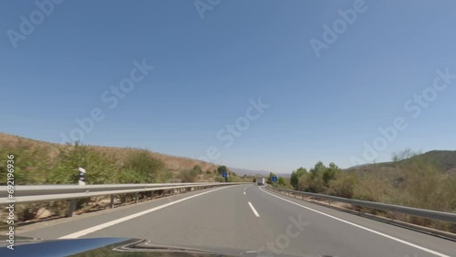 First person view, FPV, from dashcam of car driving fast on the highway towards the Tabernas desert in Almeria, Andalusia, Spain, Europe. Road trip video in POV, with bright, sunny, clear sky photo