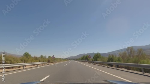 First person view, FPV, from dashcam of car driving fast on the highway towards the Tabernas desert in Almeria, Andalusia, Spain, Europe. Road trip video in POV, with bright, sunny, clear sky photo