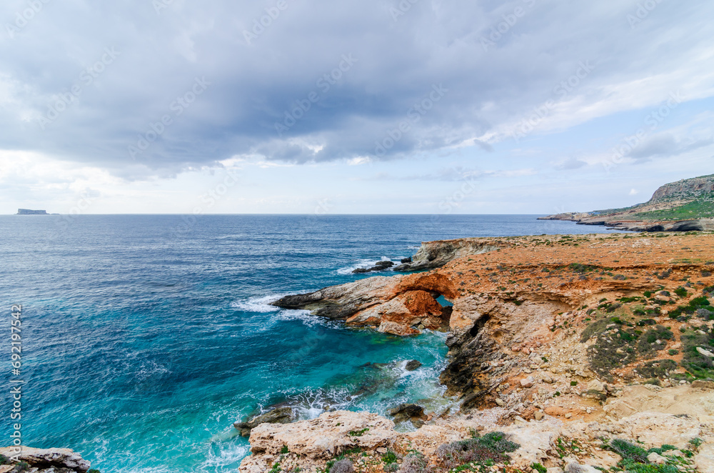 The Xaqqa Cliffs: Breathtaking view of the steep and rocky coastline and the ocean with crystal clear turquoise blue water. Climbing experience on the island of Malta. A paradise in europe.