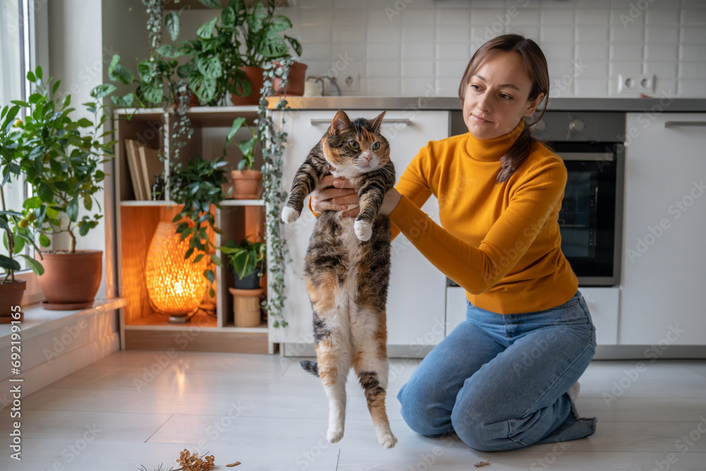 Pet lover siiting on floor, holding lazy uninterested old fat cat