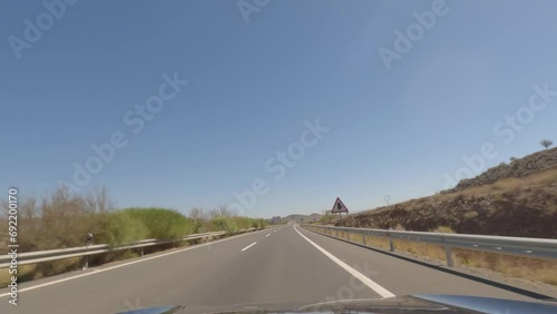 First person view, FPV, from dashcam of car driving fast on the highway towards the Tabernas desert in Almeria, Andalusia, Spain, Europe. Road trip video in POV, with bright, sunny, clear sky photo