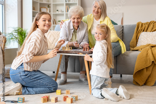 Little girl with her family playing chess at home