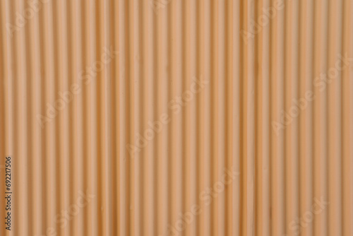 Fototapeta Naklejka Na Ścianę i Meble -  A close-up of a peach-toned corrugated surface creates a minimalistic and modern abstract background