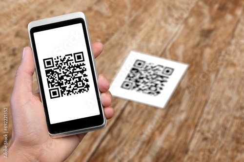 Human hand holding mobile phone with black qr code