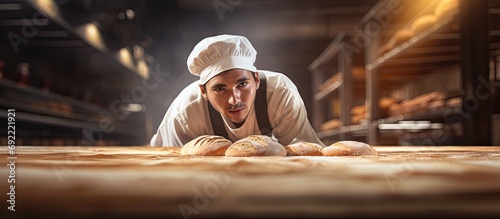 Baker putting bread in the bakery oven cowering on the floor of the bakery. Copy space image. Place for adding text or design photo