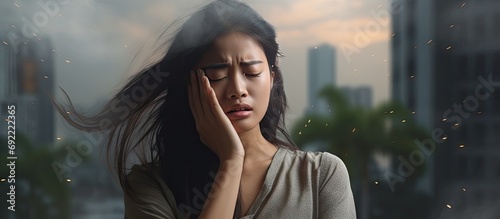 Asian woman having headache and illness while wearing mask for prevent bad air pollution PM2 5 levels meaning the air quality posed a health hazard. Copy space image. Place for adding text or design photo