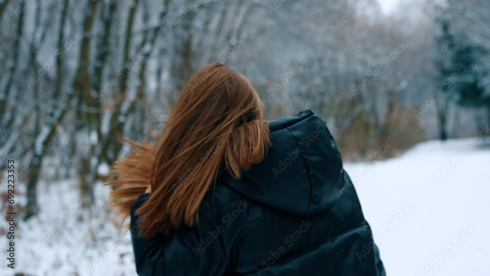Young dark-haired woman in black jacket outdoors in winter. Lady turns around touching her long hair. Young dark-haired woman in black jacket outdoors in winter. Lady turns around touching her long hair.