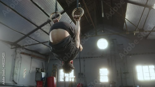 Young professional gymnast performing backward and forward rolls on rings while mastering artistic gymnastics skills in the gym photo