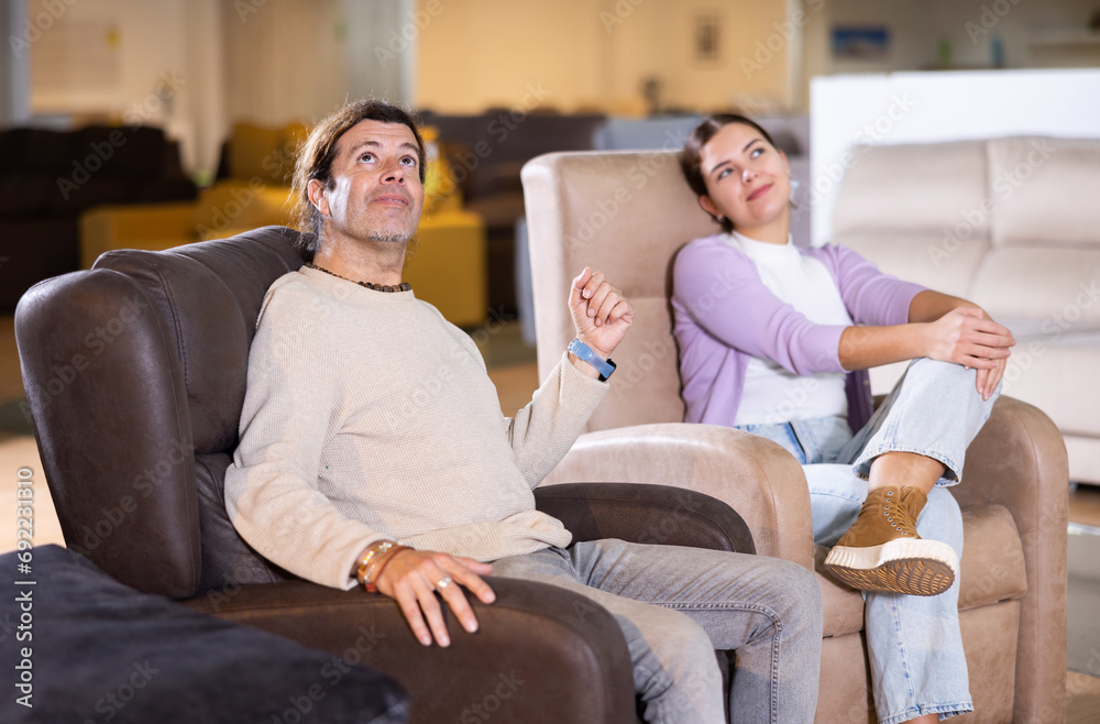 Obraz premium Man and woman sitting around in armchairs in furniture store