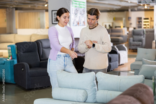 man and woman in furniture salon decide which of sofas they like more