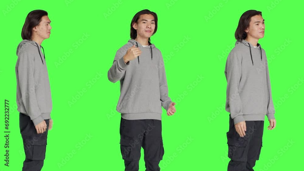 Asian guy asking people to come over, encouraging person to get closer while he is standing against greenscreen backdrop. Model in casual clothes urging somebody to approach him. Asian guy asking people to come over, encouraging person to get closer while he is standing against greenscreen backdrop. Model in casual clothes urging somebody to approach him.
