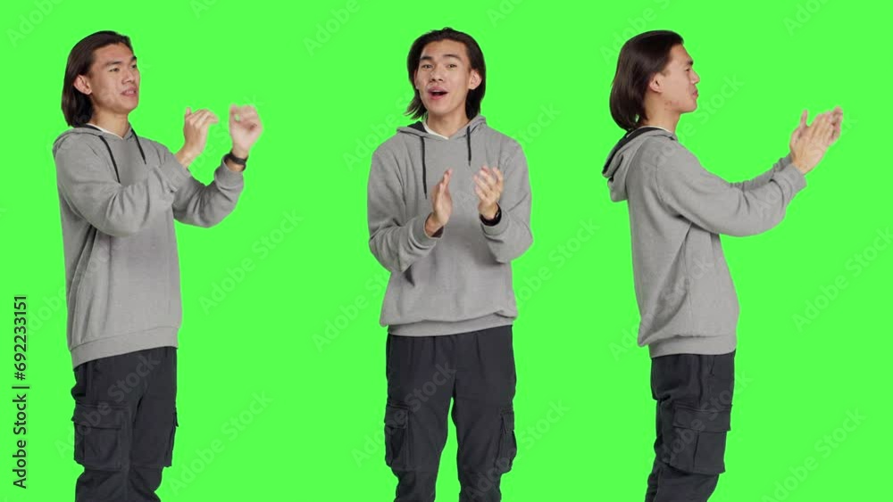 Asian cheerful man applauding someone, clapping hands to show his support and cheering person over greenscreen backdrop. Young adult feeling optimistic and happy, standing ovation. Asian cheerful man applauding someone, clapping hands to show his support and cheering person over greenscreen backdrop. Young adult feeling optimistic and happy, standing ovation.