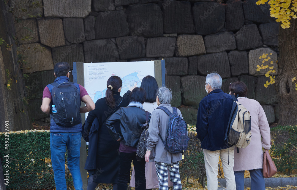 秋の皇居外苑の案内板を見ている観光客たちの姿 秋の皇居外苑の案内板を見ている観光客たちの姿