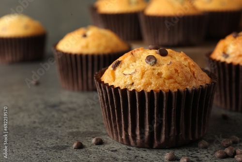 Delicious freshly baked muffins with chocolate chips on gray table, closeup