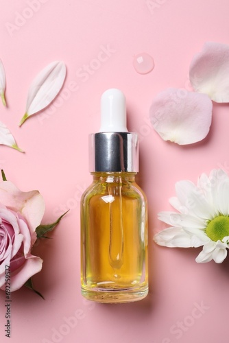 Bottle of cosmetic serum and beautiful flowers on pink background, flat lay