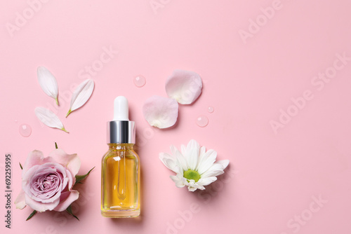Bottle of cosmetic serum and beautiful flowers on pink background, flat lay. Space for text