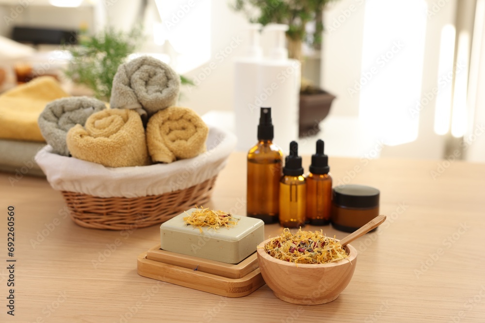 Soap bar, dry flowers, bottles of essential oils, jar with cream and towels on wooden table indoors. Spa time Soap bar, dry flowers, bottles of essential oils, jar with cream and towels on wooden table indoors. Spa time