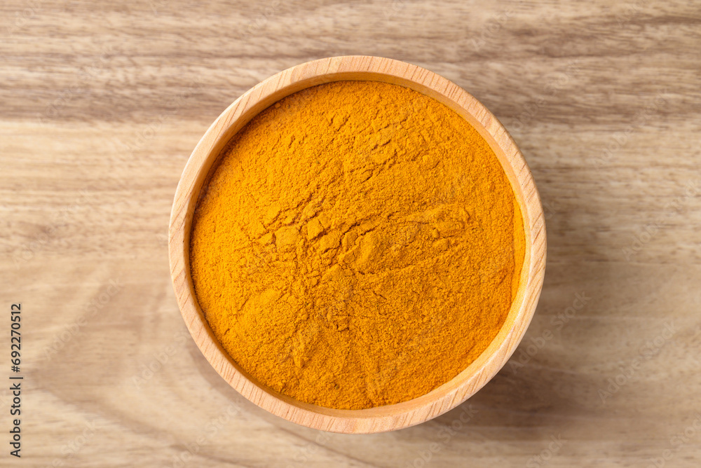 Turmeric powder in wooden bowl, Spice in Asian cuisine, Table top view Turmeric powder in wooden bowl, Spice in Asian cuisine, Table top view