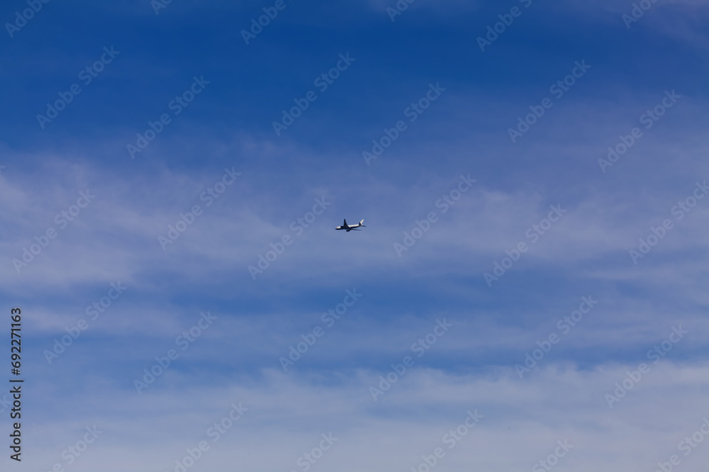 Distant Shot Of Commercial Airliner In Cloudy Blue Sky