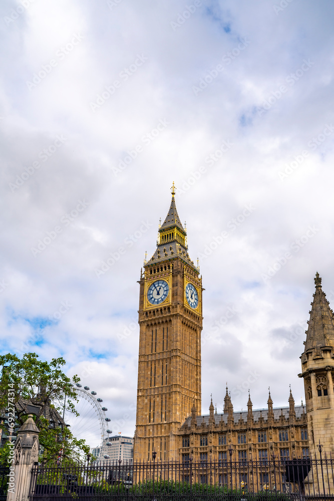 Low angle of aged building of famous Big Ben against clock tower located on street of London against blue sky background
