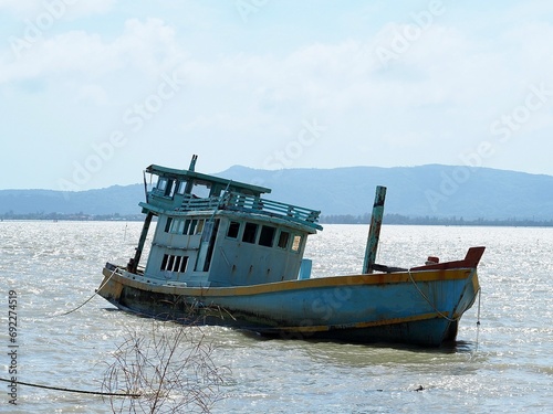 A photograph of a dilapidated fishing boat wreck  reaching the end of its service life  abandoned by the fishermen on the shoreline