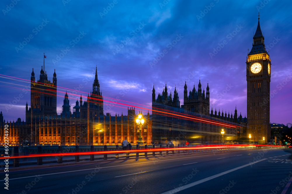 Exterior of historic buildings with glowing lights located against Big Ben tower at night in London city