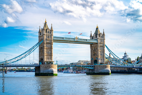 Amazing view of Tower bridge with flags over rippling river against cloudy blue sky in London photo