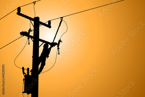 Silhouette of power lineman uses a clamp stick grip all type to install the line cover on energized high-voltage electric power lines. To change the lightning arresters that is damaged. photo