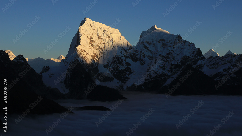 Fototapeta premium Sun lit peak of Mount Cholatse at sunset, Nepal.