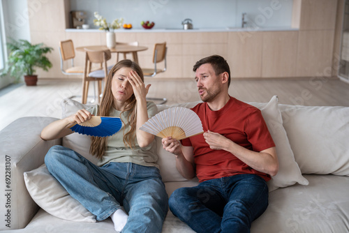 Fotografi Overheated couple suffering from hot sultry air, waving with hand fans