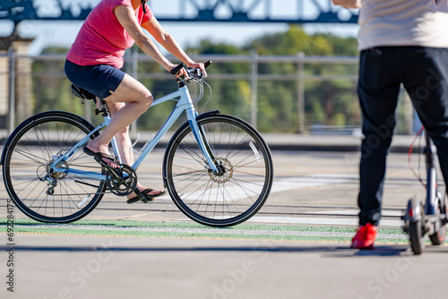 An elderly woman prefers cycling and outdoor exercise to maintain health and the whole body in good shape rather than riding an electric scooter
