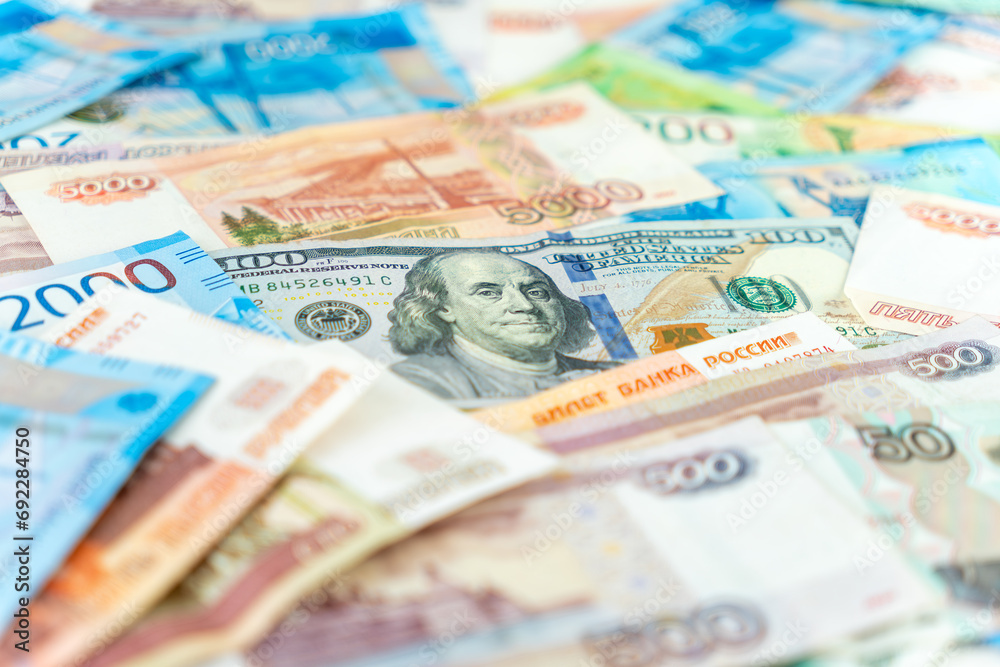 One hundred dollar bill under some five thousand ruble banknotes. currency exchange concept. Close up.