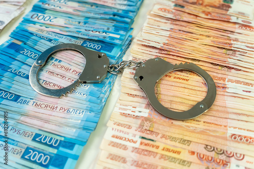 metal handcuffs against the background of the cash currency russian ruble. concept of bribery or criminal money. photo