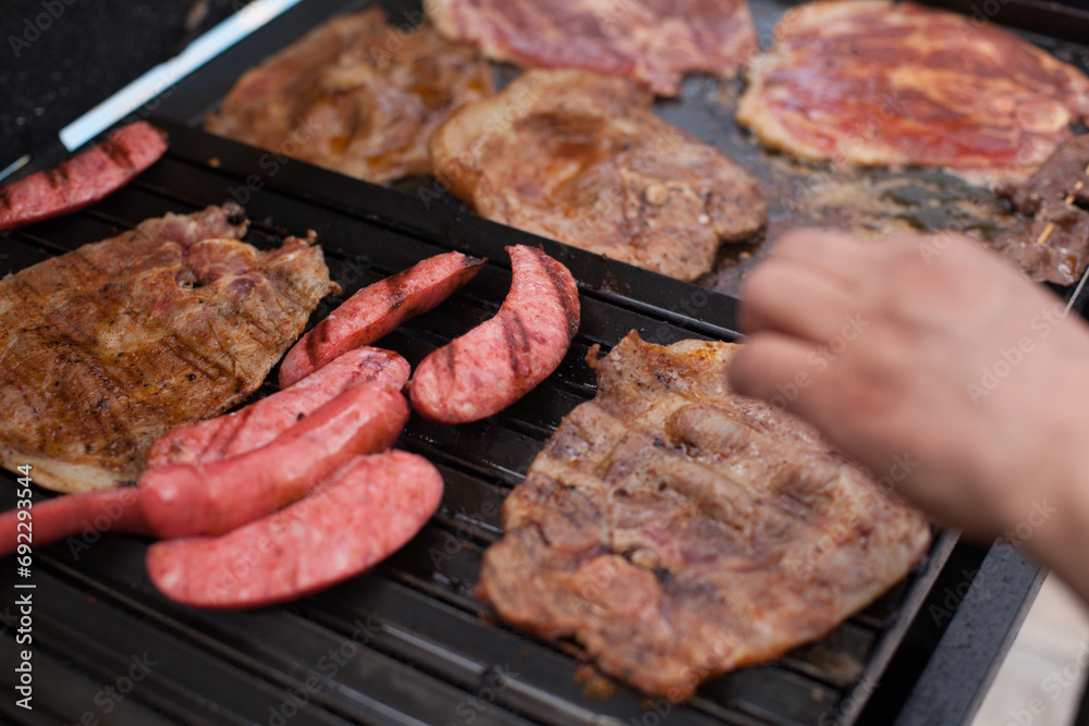 Photograph of grill with pork and sausages cooking. Food preparation concept.