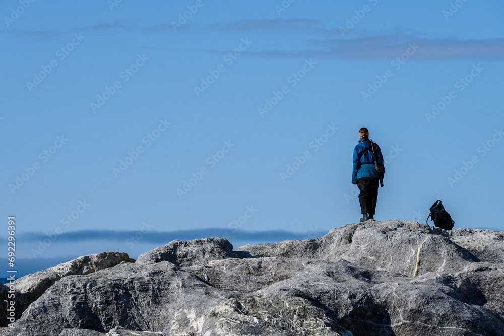 Obraz premium Expedition team member standing as lookout, and protection, from polar bears on the beach at Gnalodden, Svalbard, Arctic Ocean 