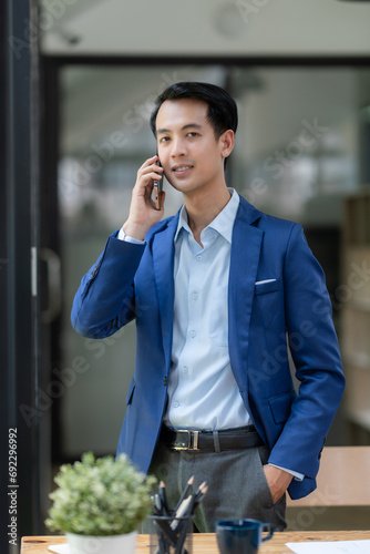 Handsome Asian Businessman Talking on Phone in Modern Office. Corporate Communication and Technology Concept.