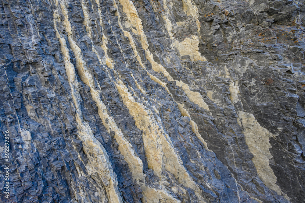 Swirling color in light and dark in a natural rock formation, cream colored and dark gray, as a nature background
