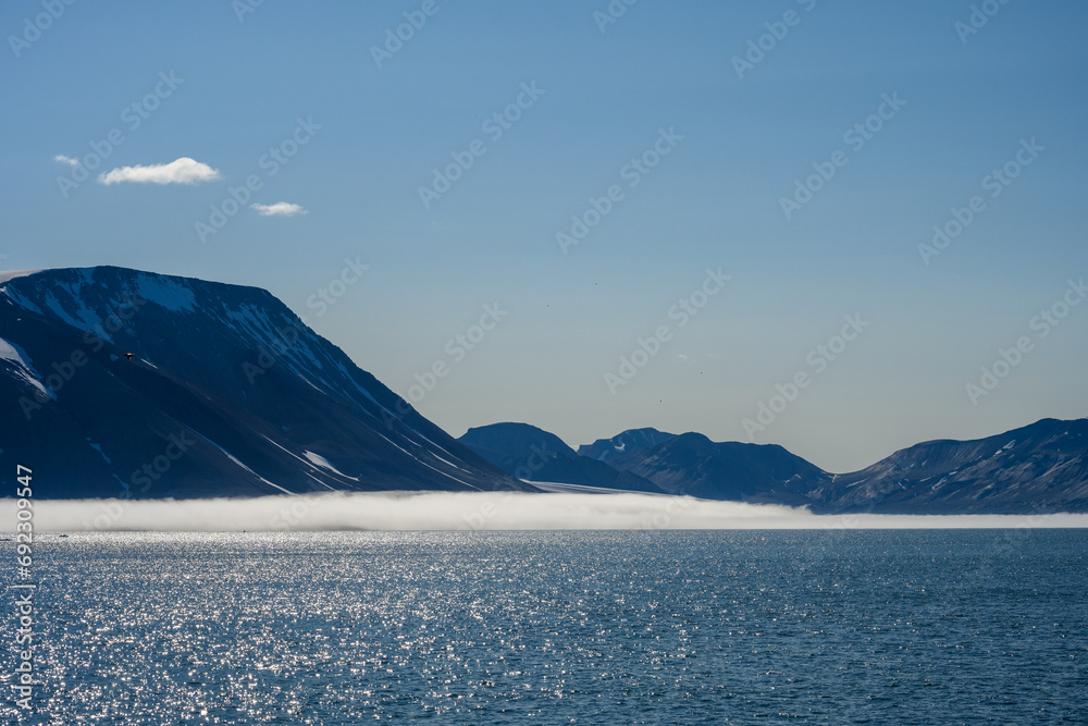 Peaceful early morning pastel blue landscape of mountain range, fog, sky, and Arctic ocean, Svalbard, as a polar nature background
 - obrazy, fototapety, plakaty 