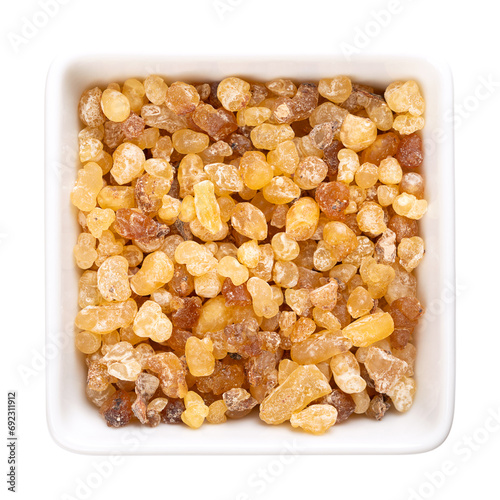 Frankincense resin in a white bowl. Small pieces of hardened aromatic olibanum resin, obtained from trees of the genus Boswellia. The so called tears are used in incense, perfumes and incense burners. photo