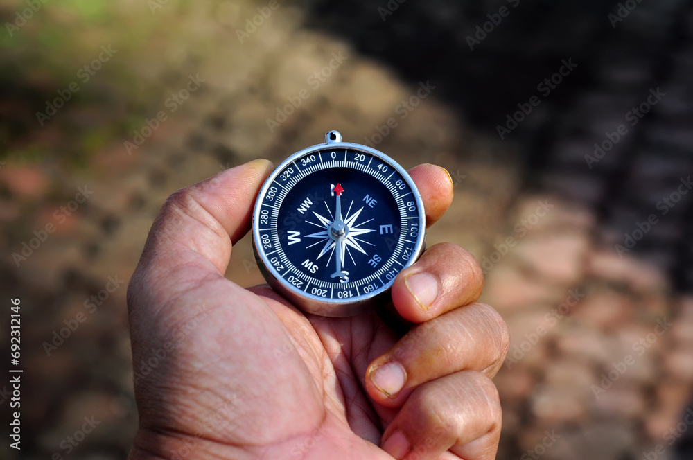 Hand holding a compass with blur background Hand holding a compass with blur background