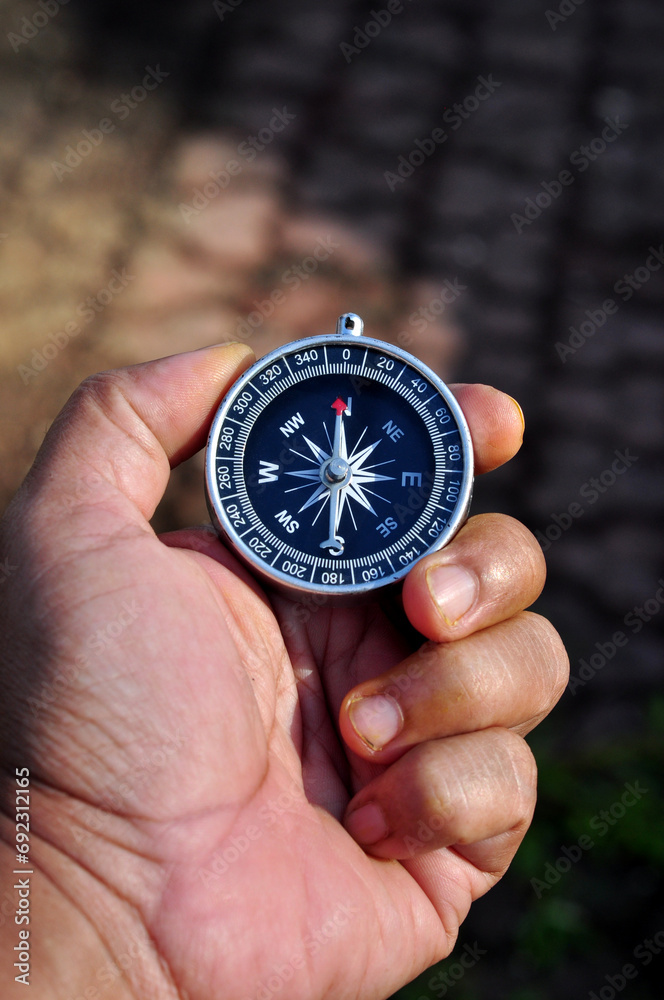 Hand holding a compass with blur background Hand holding a compass with blur background