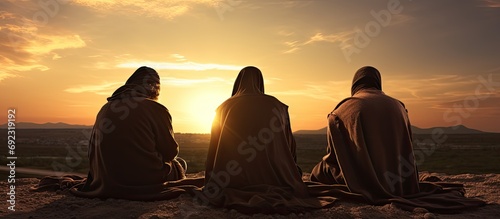 3 Jewish men praying at sunset with prayer shawls and phylacteries. photo