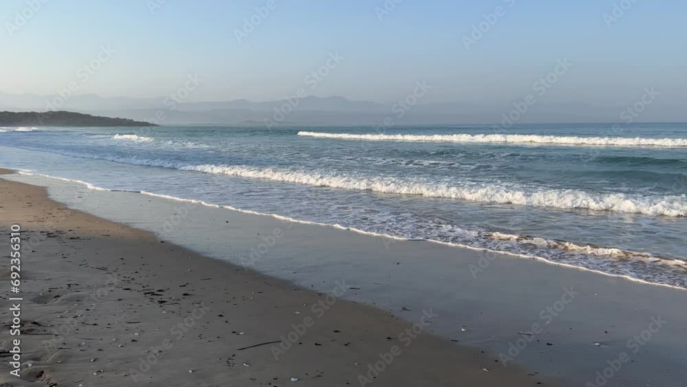 Land and sea beach with rolling waves to the shoreline and mountain views Land and sea beach with rolling waves to the shoreline and mountain views