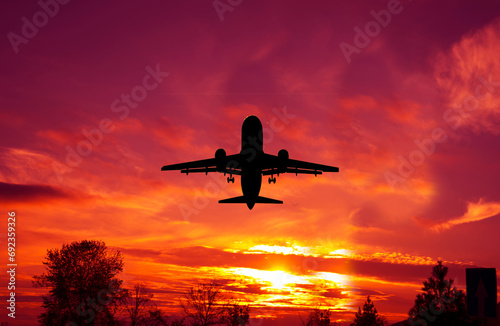 Passengers commercial airplane flying in sunset light.