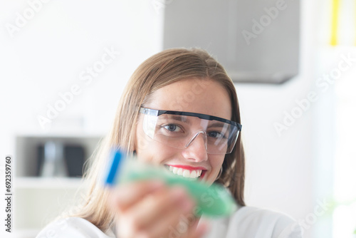 young scientist with lab glasses and holding green tube