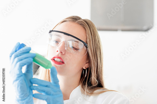 young scientist female  watching to a green liguid in a sample photo