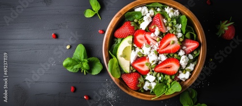 Top-down view of a salad with strawberries, spinach, cucumbers, and feta cheese, with space for additional items, photographed from above.